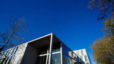 image of the top of a building against a blue sky and trees to one side
