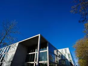 image of the top of a building against a blue sky and trees to one side