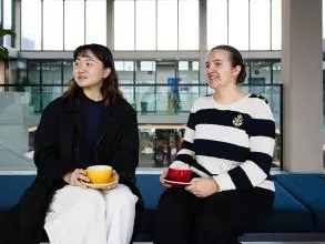 image of two students sat down on a bench facing the camera