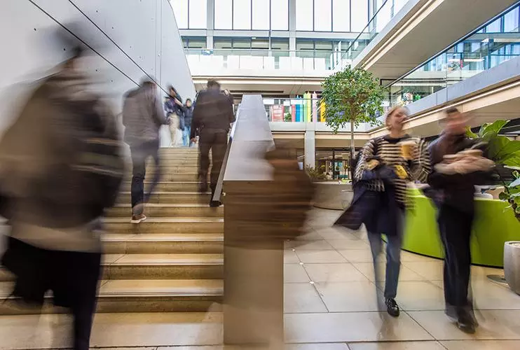 blurred image of people going up a stairwell and another couple of people walking towards the camera to the side of the stairs